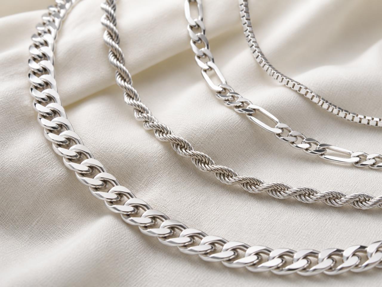Assorted silver rope, figaro and cuban link chains on ivory linen
